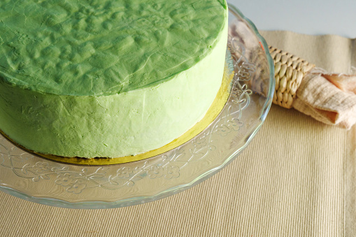 Green cake takes center stage on a glass plate, showcasing its vibrant hue and delicate elegance.