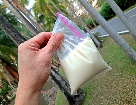 Woman is holding a fresh milk in the bottle close up.