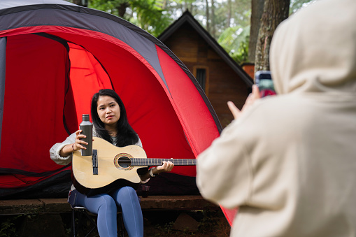 female friendship sitting together in nature with guitar