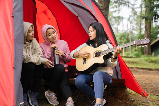 female friendship sitting together in nature with guitar