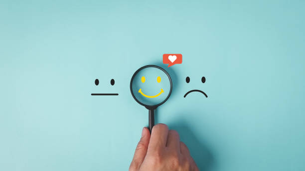 istock A hand holds a magnifying glass over a smiley face with a heart, symbolizing the search for positivity among neutral and sad expressions in customer service satisfaction feedback concept. 2017043976