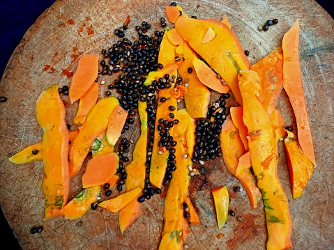 Papaya peels and seeds on cutting board.