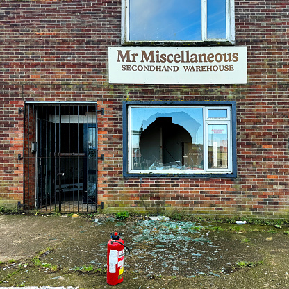 Abandoned warehouse with a broken window and fire extinguisher. Great Yarmouth February 2024