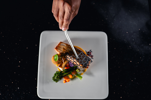 Chef is finishing the plate. Decorating the plate just before the serving.