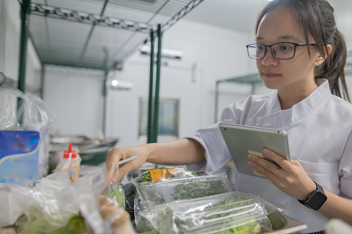Asian female apprentice kitchen checking cooking ingredient in  fridge room