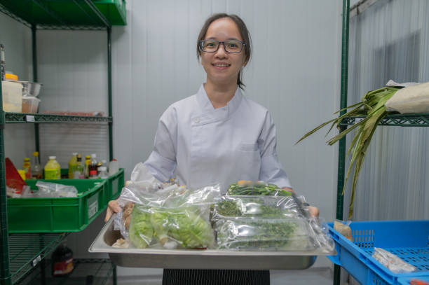 aprendiz de cocina asiática sosteniendo una sartén de verduras - hygiene food chef trainee fotografías e imágenes de stock