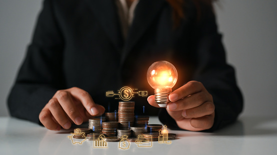 Investment and business Innovation ideas concept. Businesswoman hand holding glowing light bulb with virtual icons.