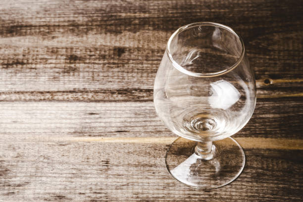 istock Empty brandy glass on rustic wood. Cognac alcohol background. Antique wooden plank with alcohol glass. 2017301588