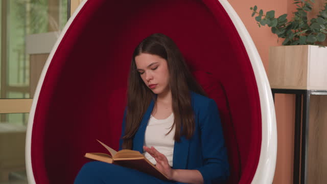 Lady in office uniform reads book in armchair