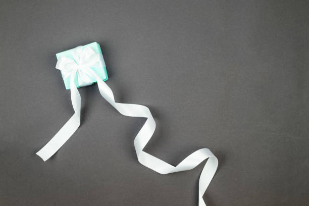 istock Holidays gift box wrapped in blue paper with white ribbon bow on grey background with room for your festive message. 2017327982