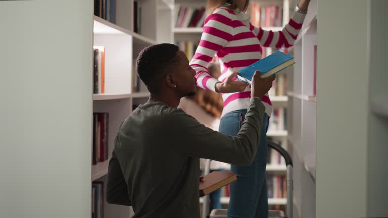 Woman takes books from upper shelf for customer