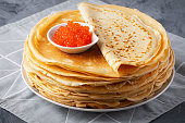 Pancakes with red caviar on grey background