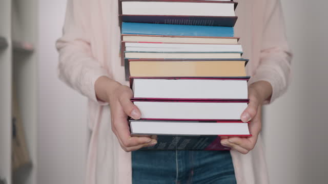 Book stack in woman hands in library closeup