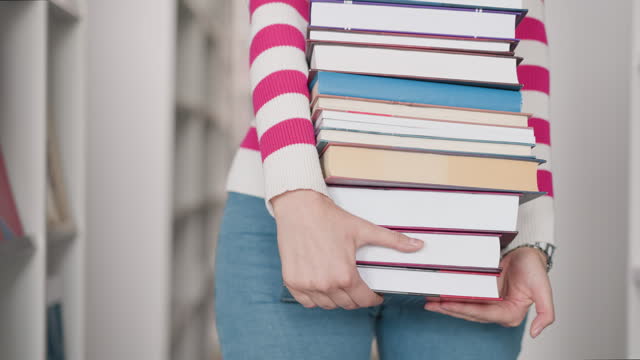 Heavy textbook pile in woman hands