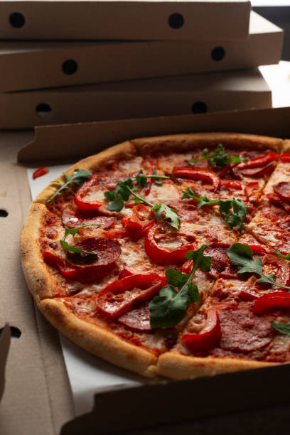 istock Large Pizza in open carton box on kitchen table closeup view 2017385429