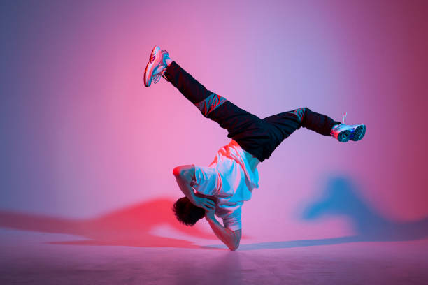 istock young guy dancer is dancing break in neon lighting, male acrobat is doing trick and dance exercise 2017396825