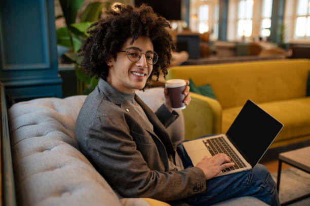 istock Young curly-haired man sitting in a hotel hall and drinking coffee 2017428513