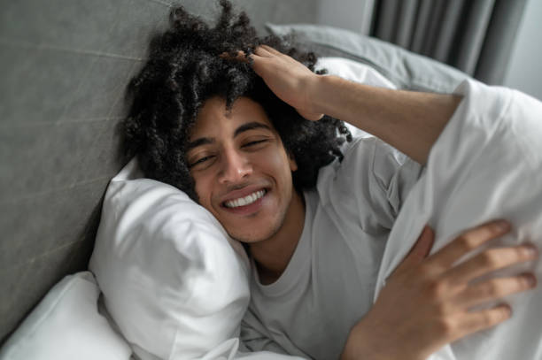 istock Young brunette man lying in bed and looking sleepy 2017429643
