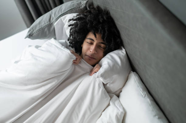 istock Young brunette man lying in bed and looking sleepy 2017429655