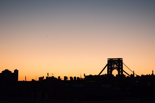 The skyline of Fort Lee with George Washington Bridge silhouetted against a sunset sky