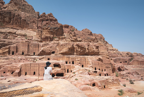 Female tourist at Petra famous archaeological site in Jordan's southwestern desert. Dating to around 300 B.C., it was the capital of the Nabatean Kingdom. A woman immerses herself in the awe-inspiring beauty of Petra, Jordan, amidst its ancient ruins and remarkable rock-cut architecture