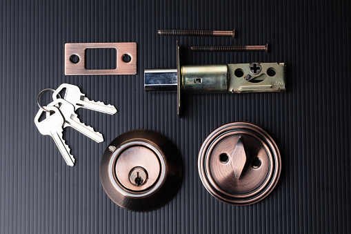 Small parts of Deadbolt lock to protect security safety on door window house. Incomplete many parts of deadbolt lock before assemble to door window with key over black background