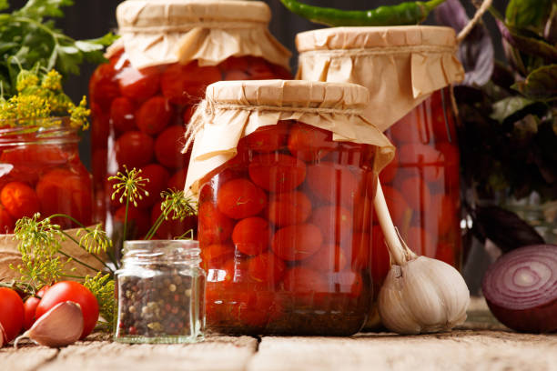 istock Pickled cherry tomatoes in jars and spices on a wooden background 2017548123