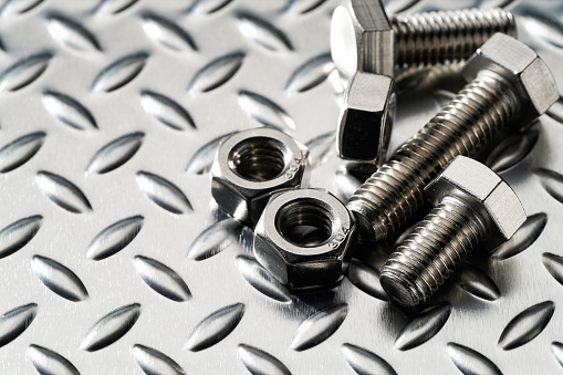 Steel nuts and bolts closeup on metalic background