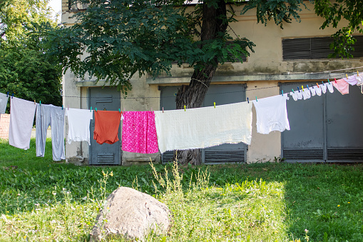 A housewife removes dry laundry from a clothesline that was drying in the backyard of the house.