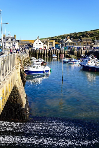 Fishing boats moored in the harbour with town buildings to the rear and the sluice gate to the left, West Bay, Dorset, UK, Europe