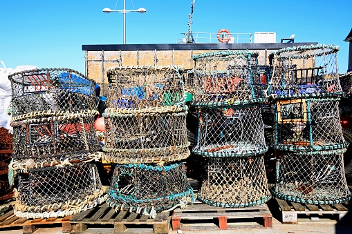 Collection of lobster pots stacked along the harbourside, West Bay, Dorset, UK, Europe.