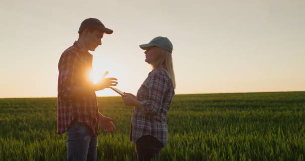 istock Two farmers are talking near a wheat field. Use a tablet 2017574602