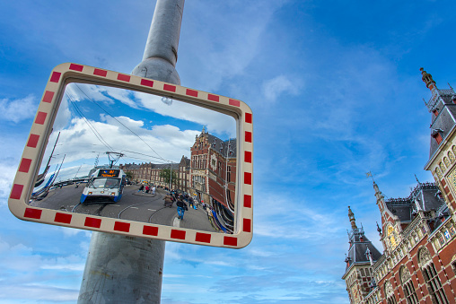 Tram in front of the Central Station, seen in a mirror at the Stationsplein