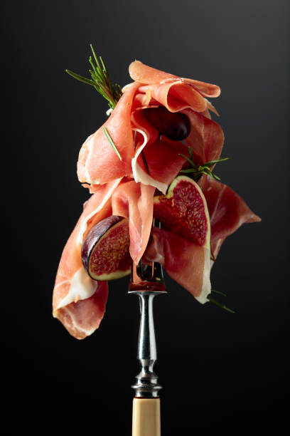 istock Prosciutto with figs, rosemary, and red olives on a fork. 2017581932