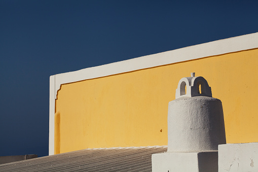 Santorini, Greece- September 20, 2017: Yellow roof contrasting with the clear blue sky in Santorini, Greece.