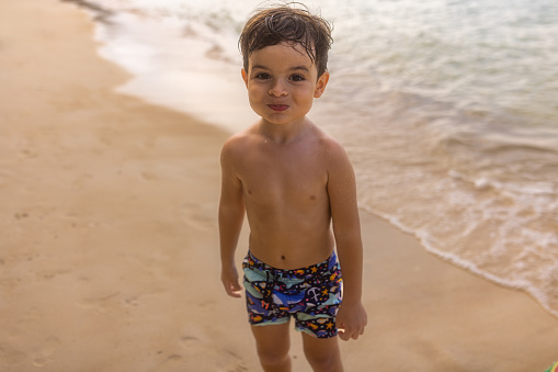 Portrait of a cute little boy on the beach by the sea, he is on vacation in Thailand.