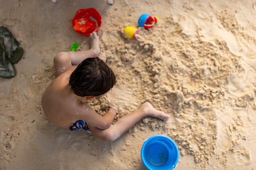 Cute little boy on the beach in sand, he is on vacation in Thailand.