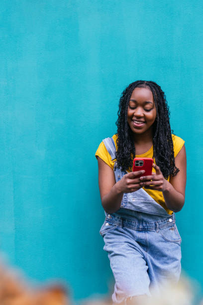 istock Smiling Woman Texting on Red Phone, Light Turquoise Wall 2017619308