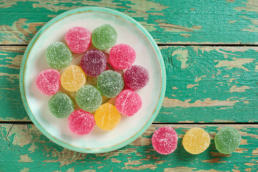 Bowl of mixed jelly sweets on mottled grey surface. Flat lay with copy space