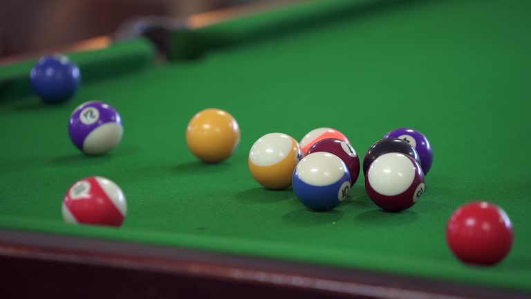 Slow motion pool balls scatter on a green felt pool table after a break, a popular social game in pubs