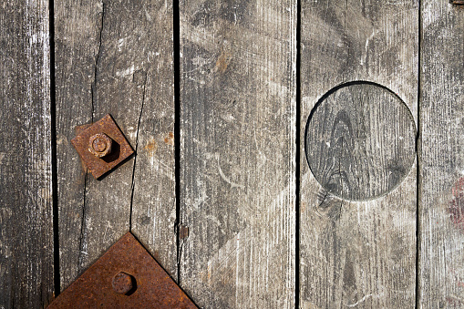 An old and cracked wooden panels with rusty nut and bolt in it as a background