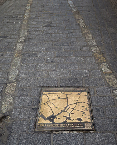 a plaque on a street marking the boundary of the Jewish Quarter, the light bricks are traces of the walled enclosure, in the old Jewish neighborhood of Santa Cruz, Seville, Spain
