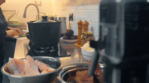 A woman prepares dinner while talking on the phone in her kitchen.