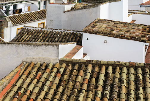 close up view of tiled roofs with one having laundry hanging on a line to dry, in the historic downtown district of Seville, Spain