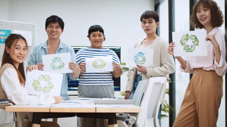 Group portrait of young millennial generation Z business people hold recycle symbol with smile. Net zero, waste recycling campaign, carbon neutrality global warming, environmental conservation concept