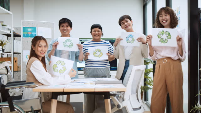 Group portrait of young millennial generation Z business people hold recycle symbol with smile. Net zero, waste recycling campaign, carbon neutrality global warming, environmental conservation concept
