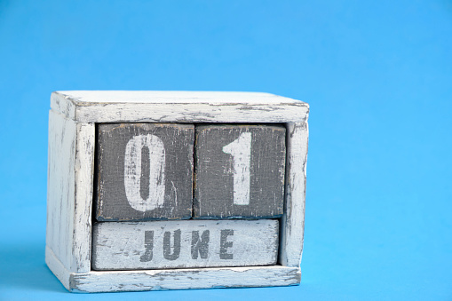 Calendar for June 01 made wooden cubes standing blue background. With empty space for text