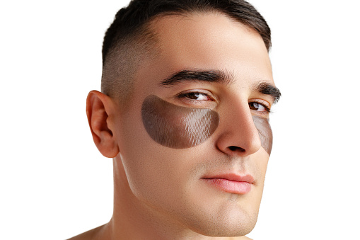 Portrait of attractive young male model with eye patches on white background close up