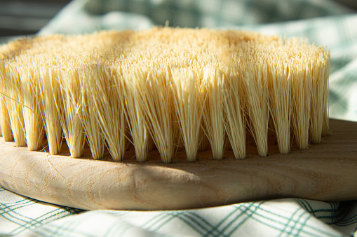 Dry natural bristle brush with wooden handle for anti cellulite massage. Close-up of massage brush for skin. Bath brush