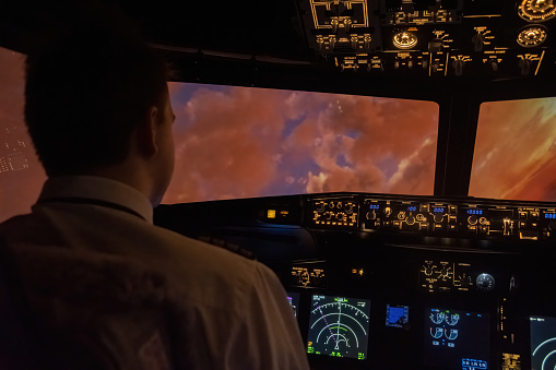 Young pilot flies airplane among clouds during sunrise. Captain navigates through cotton-like clouds touched by gentle glow of rising sun